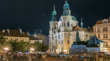 Barok Aziz Nicholas Katedrali Prag ile anıt Oldtown meydanında Jan Hus gece timelapse aydınlatılmış. Turistler dolaşmak