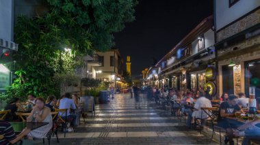 Kaleiçi timelapse hyperlapse Kesik Minare Camii cami Antalya'da kırık Minare üzerinde gece manzaralı tarihi cadde boyunca yürüyüş. Etrafta dolaşan insanlar