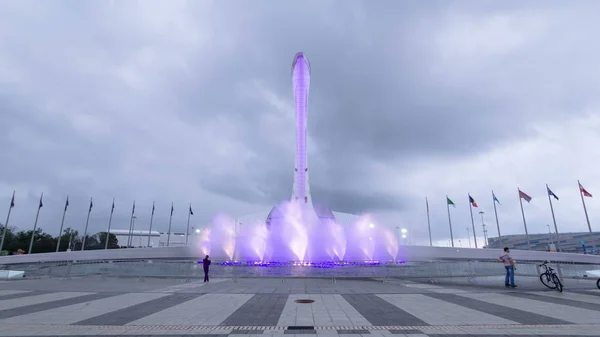 Olympic Torch with fountains in light in Olympic park fisht stadium in the background timelapse. Sochi, Russia 4K