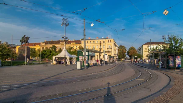 New modern trams of Croatian capital Zagreb timelapse near railway station. People at tram stop at sunset time. ZAGREB, CROATIA