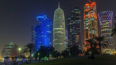 Doha 'nın yüksek katlı bölgesinde gece vardiyası, parktan görülmüş. Batı körfezinde aydınlatılmış gökdelenler ve palmiyeler