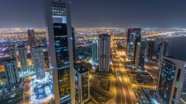 Katar 'ın Doha Zaman Çizelgesi' nde Batı Körfezi bölgesinin ufuk çizgisi. Aydınlatılmış modern gökdelenler geceleri çatıdan gökyüzü manzarası