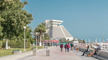 Batı Körfezi 'ndeki Doha' s Corniche. Yürüyen insanlarla vakit geçiriyor Katar. Corniche, fantastik gezinti yerleri, su sporları, geleneksel dhow yarışları ve daha pek çok şeyle bilinen popüler bir egzersiz mekanıdır.