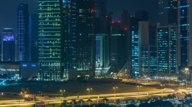 Katar 'ın Doha Zaman Çizelgesi' nde Batı Körfezi bölgesinin ufuk çizgisi. Aydınlatılmış modern gökdelenler geceleri çatıdan gökyüzü manzarası. Yolda trafik vardı.