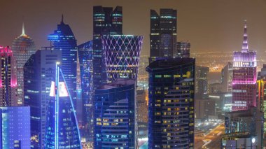 Katar 'ın Doha Zaman Çizelgesi' nde Batı Körfezi bölgesinin ufuk çizgisi. Aydınlatılmış modern gökdelenler geceleri çatıdan gökyüzü manzarası. Yolda trafik vardı.