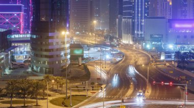Batı Körfezi bölgesinin ufuk çizgisi ve Katar 'ın Doha Timelapse bölgesinin tepesinden gelen trafik. Aydınlatılmış modern gökdelenler geceleri çatıdan gökyüzü manzarası