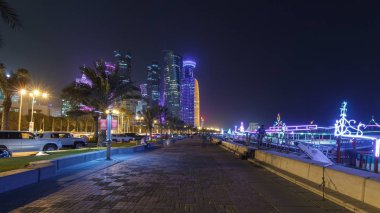 Geceleri Doha 'nın ufuk çizgisi Corniche Timelapse hiperlapse, Katar' dan görülebiliyor. Palmiyeler ve botlar yana. Aydınlatılmış gökdelenler ve kuleler