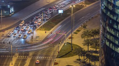 Katar, Doha Timelapse 'da West Bay yolunda trafik var. Aydınlatılmış modern gökdelenler ve gece çatıdan kesişen hava manzarası.