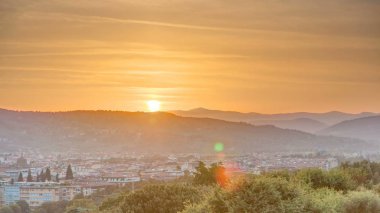 Arno nehir köprüleri ve tarihi binalarla Floransa şehrinin gündoğumu manzarası, arka planda dağlar. Yaz günü yeşil ağaçlar