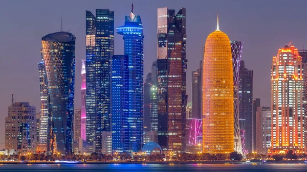 Doha downtown skyline day to night transition timelapse, Qatar, Middle East. Illuminated skyscrapers on a West Bay reflected in a water of Gulf