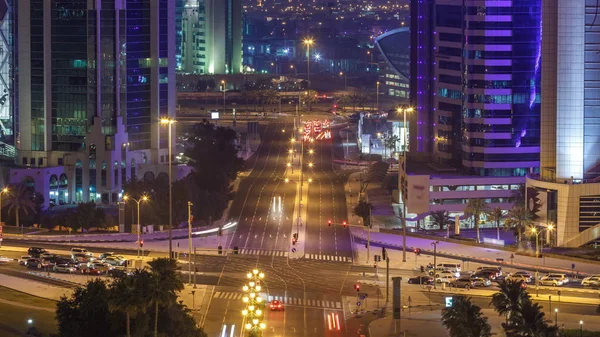 Katar, Doha Timelapse 'da West Bay yolunda trafik var. Aydınlatılmış modern gökdelenler ve gece çatıdan kesişen hava manzarası.
