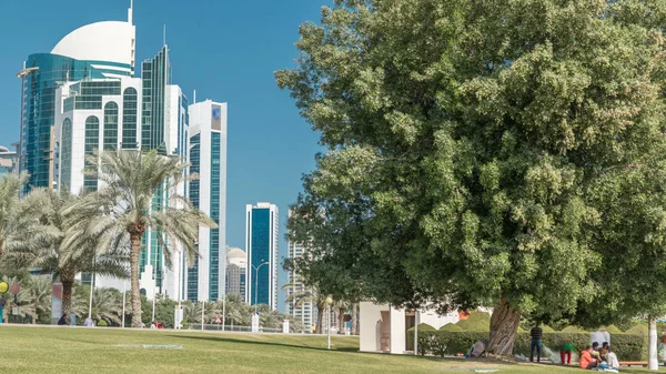 Batı Körfezi 'ndeki Doha' s Corniche 'de modern gökdelenler ve ağaçlarla, Katar. Corniche, fantastik gezinti yerleri, su sporları, geleneksel dhow yarışları ve daha pek çok şeyle bilinen popüler bir egzersiz mekanıdır.