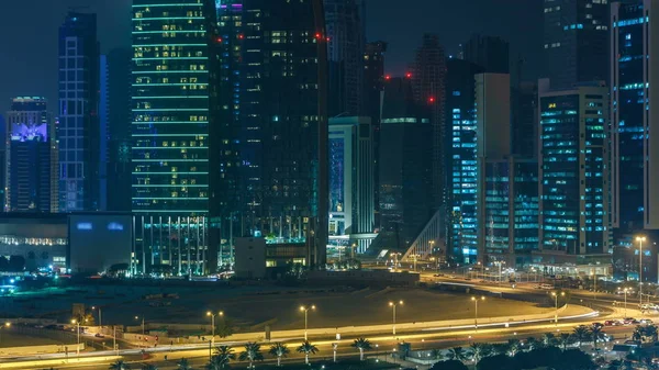 Katar 'ın Doha Zaman Çizelgesi' nde Batı Körfezi bölgesinin ufuk çizgisi. Aydınlatılmış modern gökdelenler geceleri çatıdan gökyüzü manzarası. Yolda trafik vardı.