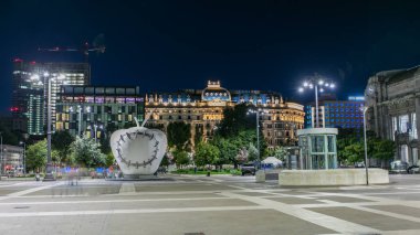 Anıtsal Reintegrated Apple Milan'ın Merkez Tren İstasyonu, Piazza Duca d'Aosta gece timelapse önünde heykel. Aydınlatılmış binalar. Yaz günü, yeşil ağaçlar
