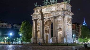 Arco della Pace in Piazza Sempione (Arch of Peace in Simplon Square) timelapse illuminated at night side view. It is a neoclassical triumph arch, 25 m high and 24 m wide, built between 1807 and 1838. Traffic on background clipart