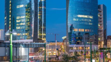 Milan Porta Nuova iş bölgesi gün gece geçiş timelapse Milan, İtalya, güneş battıktan sonra içinde modern gökdelenler ile manzarası. Yolda trafik. Işık içinde pencere eşiği. Köprüsü'nden Üstten Görünüm