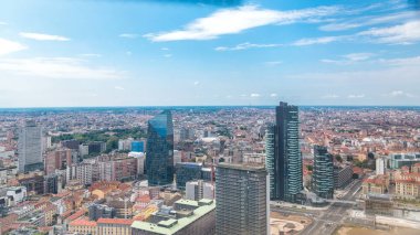 Milan modern kuleleri ve gökdelenler ve Garibaldi tren istasyonu iş bölgesi timelapse çözdüğünü çatı üzerinden, havadan görünümü. Kırmızı çatılar ile evler. Mavi bulutlu gökyüzü yaz gün