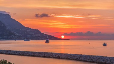 Beaulieu sur mer, Fransa 'dan deniz ve manzaranın gün doğumu görüntüsü. Tekneler ve yatlar ön planda. Sudaki yansımalar.