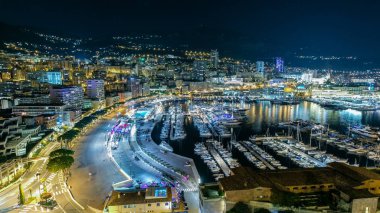 Monte Carlo 'nun Panorama' sı geceleyin Herkül Limanı ile Monako köyündeki gözlem güvertesinden. Liman manzaralı, aydınlık binalar ve yatlar. Trafik vardı.