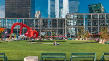 La Defense 'ın gökdelenleri ve zaman ayarlı bankları olan yeşil çimenler - Paris, Fransa' nın banliyölerindeki modern iş ve yerleşim alanları. Yeşil ağaçlar, güneşli yaz gününde mavi bulutlu gökyüzü
