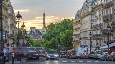 Güneş, arka planda Eiffe kulesi olan Paris Sufflot Caddesi 'ndeki bir binanın arkasında batıyor. Yaz gününde bulutlu turuncu gökyüzü