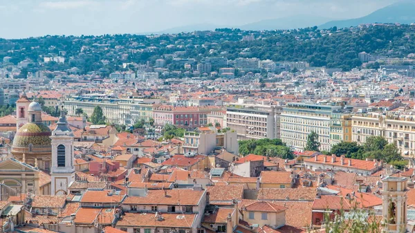 Bright sun lights red roofs of the old city timelapse. Aerial view from Shatto\'s hill. Mountains on background. Summer day. Nice, France