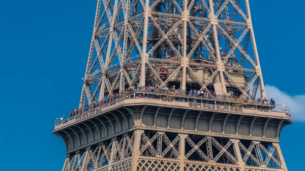 Close up view of middle section of the Eiffel Tower with tourists on observation deck timelapse in Paris, France. Sunny summer day with blue clody sky