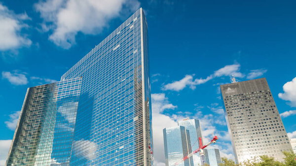 Unique skyscraper timelapse in famous financial and business district of Paris - La Defense. Reflections on a glass with blue clouds and blue sky at summer day
