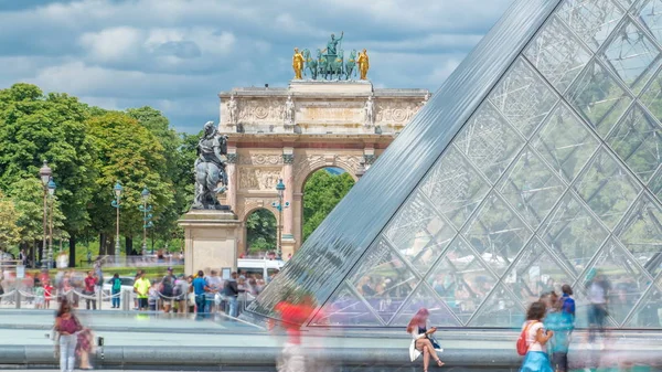 ルーブル ピラミッドと凱旋門は パリで時間が経過した反射のあるカルーセルです ピラミッドはルーヴル美術館の正面玄関として完成した 夏の日に噴水の近くに座っている人 — ストック写真