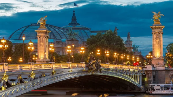 在巴黎的夜景照明天到晚上转型过程中的亚历山大桥 在背景上的大皇宫 道路上的交通 — 图库照片