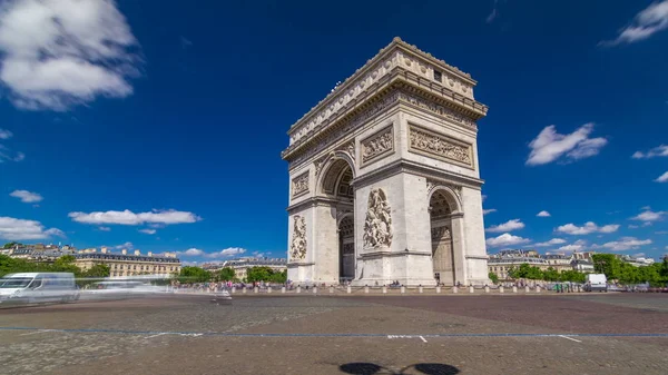 The Arc de Triomphe (Triumphal Arch of the Star) timelapse hyperlapse is one of the most famous monuments in Paris, standing at the western end of the Champs-Elyseees. Traffic on circle road. Blue cloudy sky at summer day