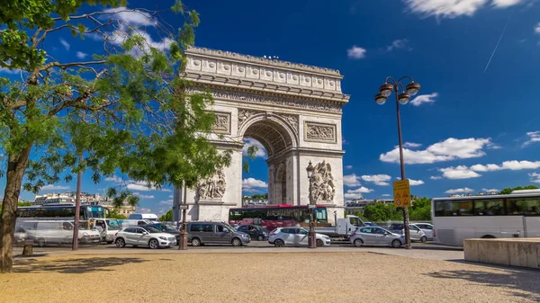 The Arc de Triomphe (Triumphal Arch of the Star) timelapse hyperlapse is one of the most famous monuments in Paris, standing at the western end of the Champs-Elyseees. Traffic on circle road. Blue cloudy sky at summer day