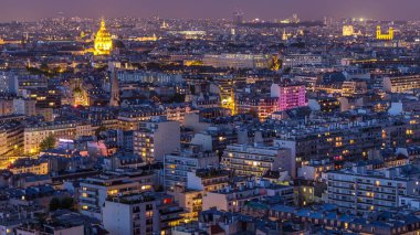Paris 'teki evlerin çatılarının üstündeki hava panoraması gece gündüz geçiş zamanı. Günbatımından sonra gece manzarası ve diğer manzaralar aydınlandı.
