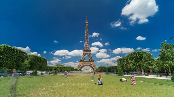 Paris 'teki Champs de Mars' taki Eyfel Kulesi. Zaman atlaması, Fransa. Yazın mavi bulutlu gökyüzü Yeşil çimenler ve etrafta yürüyen insanlar