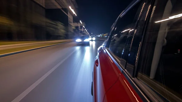 Drivelapse from side of fast car moving on a night avenue in city timelapse hyperlapse, road with lights reflected on car on high speed. Rapid rhythm of a modern city.