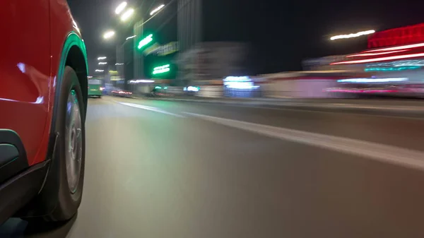 Drivelapse urban look from fast driving car at a night avenue in a city timelapse hyperlapse, road with lights reflected on car at high speed. Rapid rhythm of a modern city.