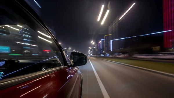 Drivelapse urban look from fast driving car at a night avenue in a city timelapse hyperlapse, road with lights reflected on car at high speed. Rapid rhythm of a modern city.