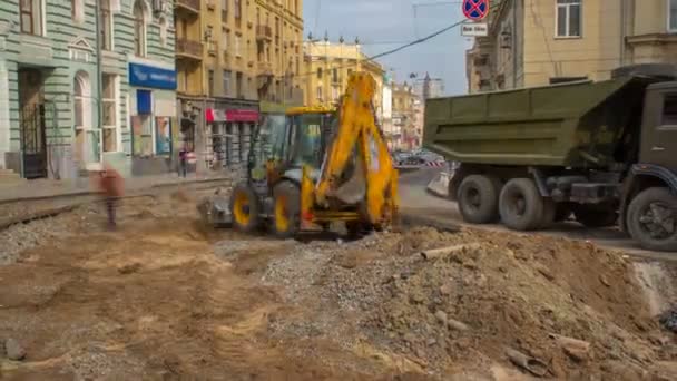Industrial truck loader excavator moving earth and unloading into a dumper truck timelapse on roud construction site. Aerial view of reconstruction of tram tracks — Stock Footage Industrial Truck Loader Excavator Moving Earth Unloading Dumper Truck Timelapse Stock Video