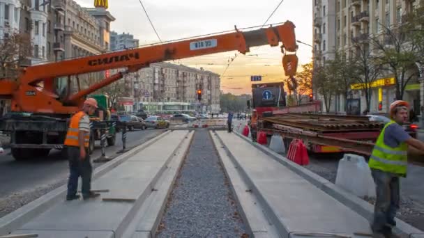 Grue mobile télescopique de construction orange déchargeant les rails de tramway du timelapse du camion . — Video