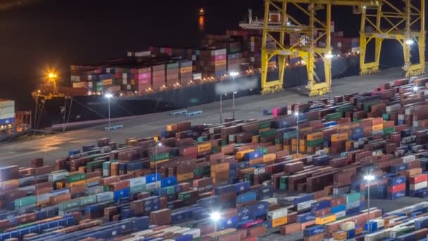 Морской порт и погрузочные доки в порту с кранами и разноцветными грузовыми контейнерами ночное время — стоковое видео