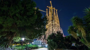 Sagrada Familia, Barselona, İspanya, gece timelapse hyperlapse büyük bir Roma Katolik kilisesinde ışıklı tepesinde. Kuleler ve vinçler. Parkı'ndan görüntülemek