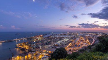 Gece geçiş timelapse liman ve yükleme rıhtım liman vinçleri ve çok renkli kargo konteyner gün ile. Güneş battıktan sonra Montjuic Tepesi'nden hava üstten görünüm. Barcelona, İspanya