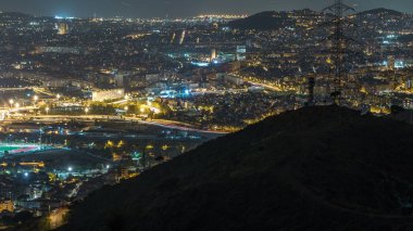 Ev ve trafik gece timelapse çatılar ile Barcelona ve Badalona manzarası. Tepenin üstüne Iberic Puig İspanya köyü açısından havadan görünümü