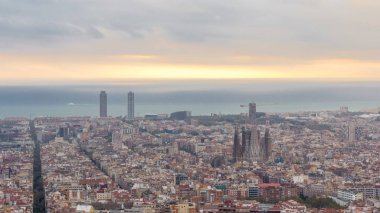 Barcelona Panoraması gündoğumu timelapse, İspanya, sırasında ışık ışınları ile bulutlu bir sabahı Carmel sığınaklar görüş. Sagrada familia Katedrali ile Hill Hava üstten görünüm. Renkli gökyüzü