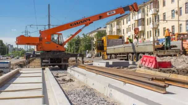 Orange construction telescopic mobile crane unloading tram rails from truck timelapse. — Stock Video