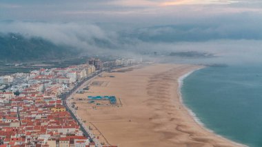 Nazare panorama görünümünü füniküler kabinleri. Sis akşam gün batımı sırasında okyanus tarafından geliyor. Portekiz Nazare Atlantic Coast en popüler deniz tatil var. Nazare manzarası ve plaj sahil Nazare Sitio üzerinden.
