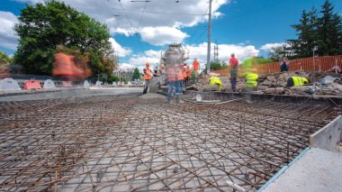 Concrete works for road construction with many workers and mixer timelapse hyperlapse. Pouring mortar to metal reinforcement. Reconstruction of tram tracks clipart