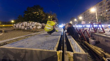 Tramvay rayları yükleme ve beton yol gece timelapse hyperlapse tabaklarda entegrasyonu son aşamada. Titreşim ve noice azaltılması için sıvı reçine ile doldurma. Tramvay yeniden inşası süreci izler