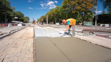 Concrete works for road construction with workers in uniform timelapse. Covering and protective coating by sprayer. Reconstruction of tram tracks clipart