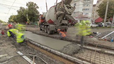 Beton yol yapım birçok işçi ve mikser timelapse hyperlapse ile çalışıyor. Harç metal takviye için dökme. Tramvay parça yeniden inşası